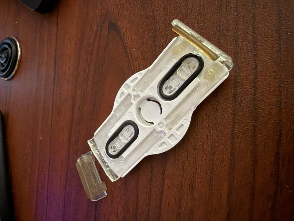 A broken PopGrip Slide Stretch showing cracked plastic, worn rubber bands, and a snapped clip arm